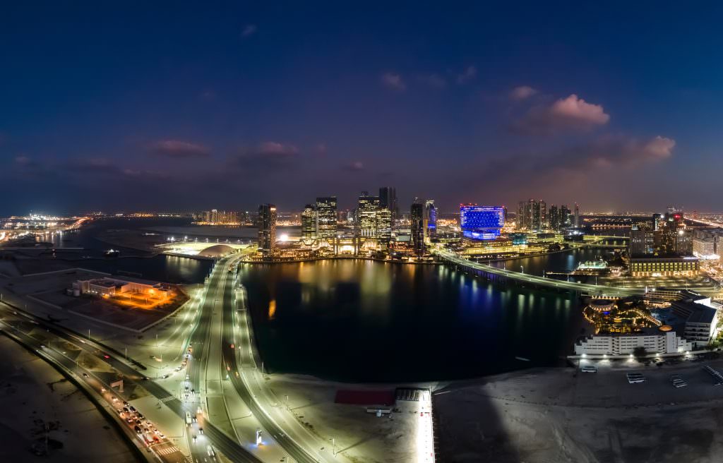 Luxury Abu Dhabi yacht charter aerial night view with marina, skyline lights and waterfront roads