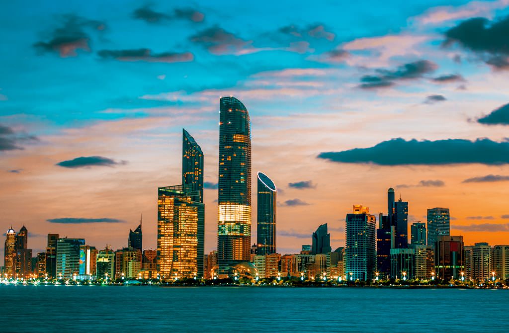 Abu Dhabi yacht charter skyline at sunset with illuminated city lights and waterfront