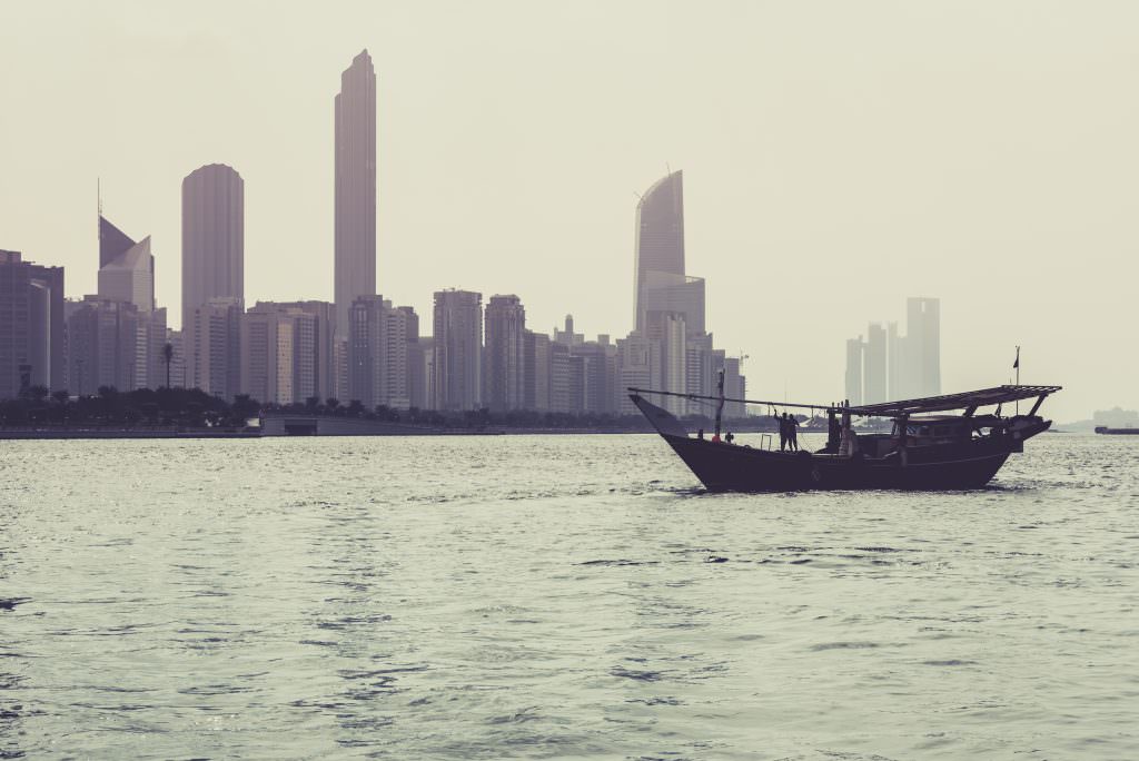 Luxury Abu Dhabi yacht charter skyline with traditional dhow boat on the sea at sunset