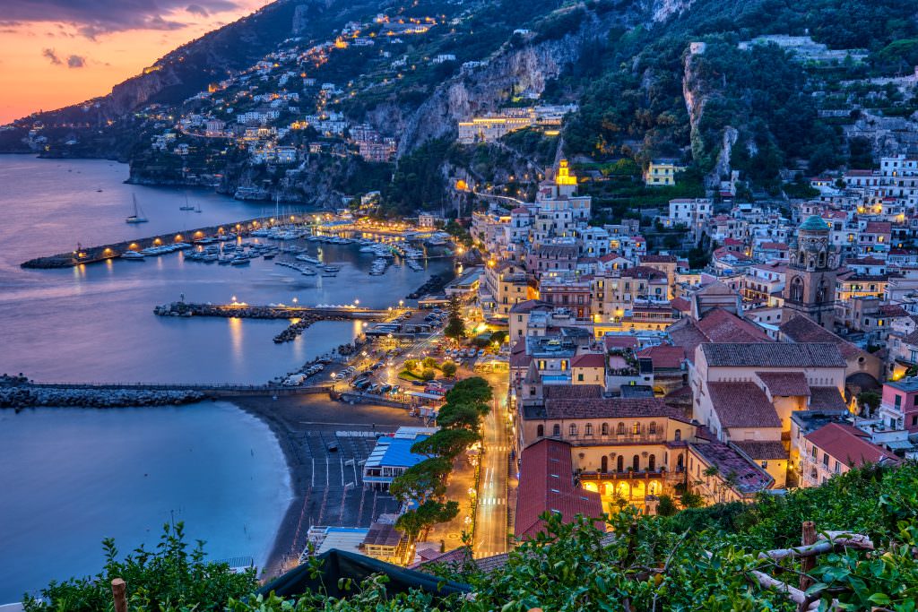 Luxury yacht charter in Amalfi Coast at night with harbor and city lights view