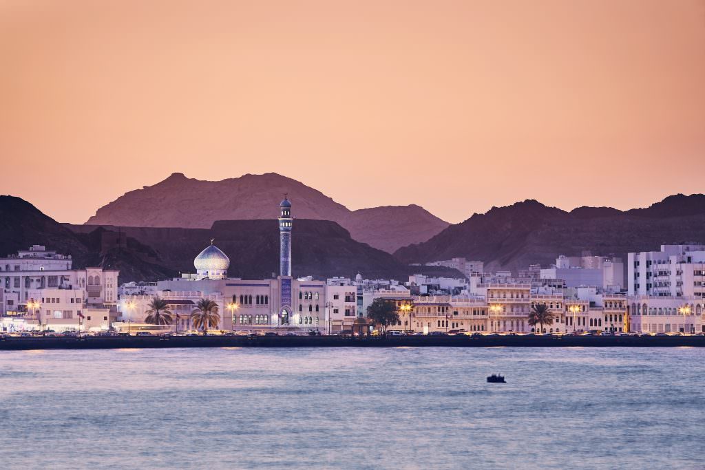 Muscat yacht charter in Oman with sunset coastline and mosque view