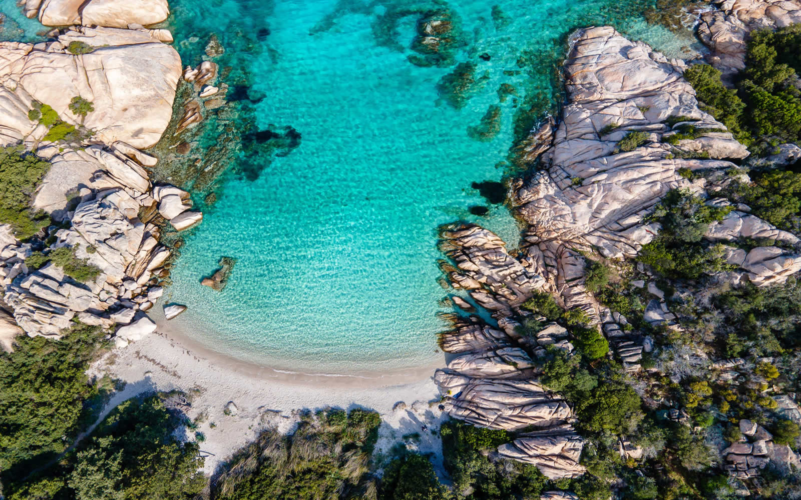 Aerial view of a secluded turquoise bay in Sardinia