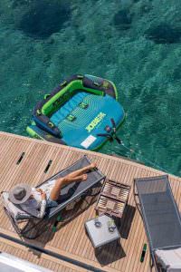 Calm Down luxury yacht charter sunbathing deck with water toys and turquoise sea in Mediterranean