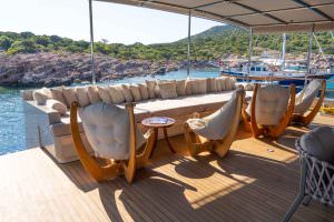 De Love motor sailer outdoor seating area, luxury yacht charter deck with comfortable lounge, armchairs and scenic coastal view
