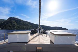 King of the Sea motor sailer front deck view, luxury yacht bow area with open sea horizon and scenic coastline, premium yacht charter experience