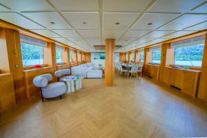 King of the Sea motor sailer interior salon, luxury yacht spacious lounge and dining area with elegant wooden design and panoramic sea views