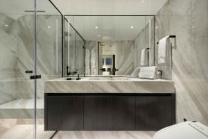 Legasea luxury yacht bathroom with marble walls, modern vanity sink, mirror and glass shower enclosure