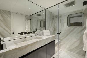 Legasea luxury yacht bathroom with marble sink, glass shower cabin, mirror and modern interior design