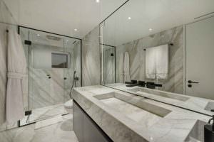 Legasea luxury yacht bathroom with marble surfaces, modern sink, mirror and glass shower design