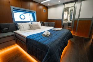 North Wind motor sailer VIP cabin, luxury yacht guest suite with elegant wooden interior, spacious bed, ambient lighting and modern bathroom access