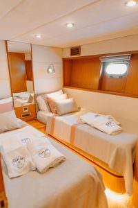 Reis yacht twin cabin with two single beds, modern wooden interior and soft lighting, luxury yacht charter experience