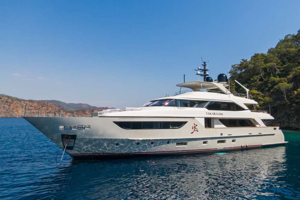 Luxury yacht Takara One side view cruising near coastline with clear blue sea